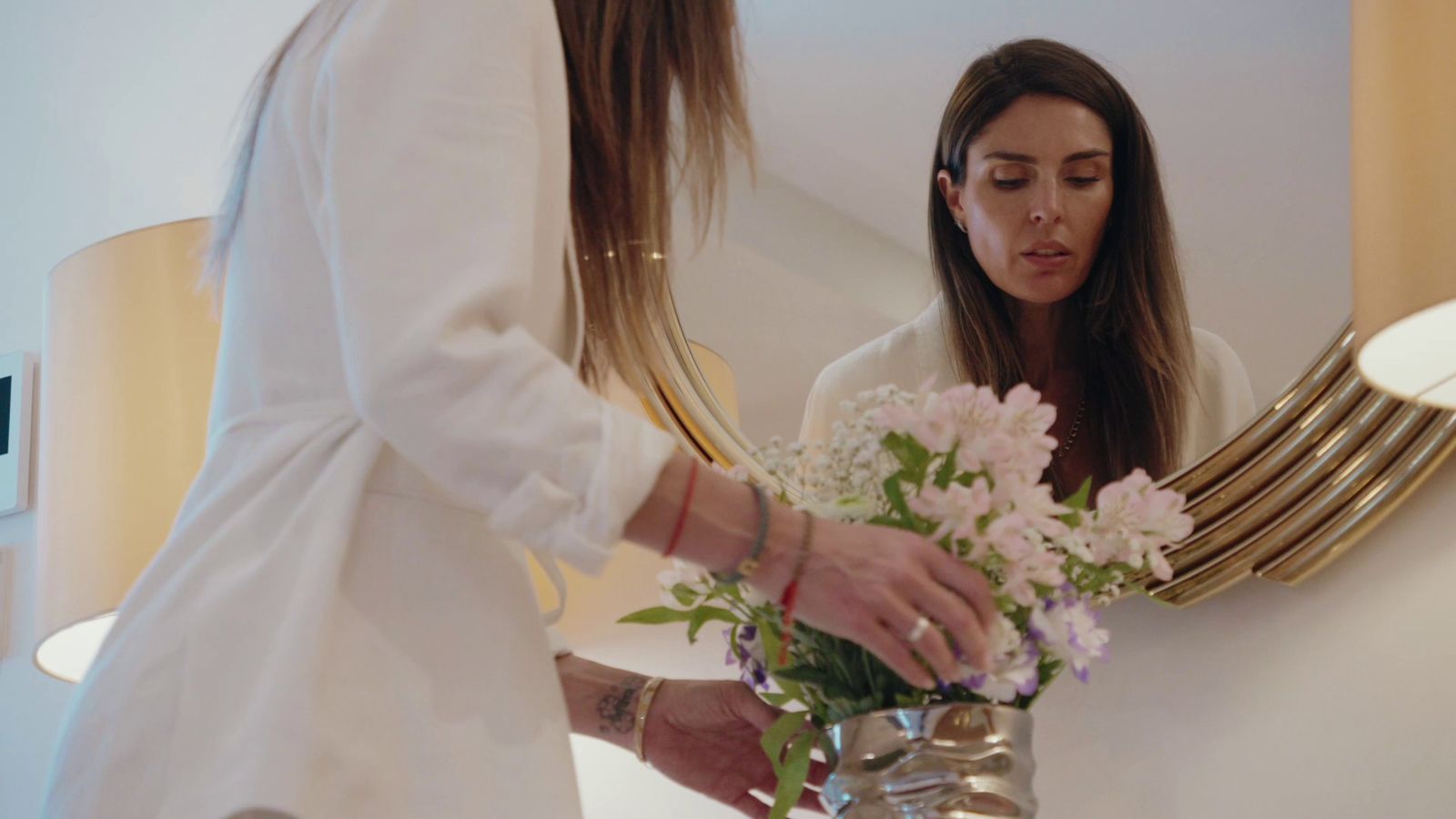 Lou compose un bouquet devant un miroir doré
